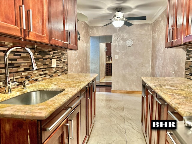 kitchen featuring light stone countertops, decorative backsplash, ceiling fan, a sink, and crown molding