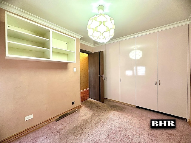 unfurnished bedroom with carpet flooring, a closet, visible vents, baseboards, and ornamental molding