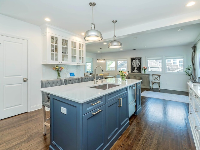 kitchen featuring a sink, white cabinetry, a breakfast bar area, dark wood-type flooring, and light countertops
