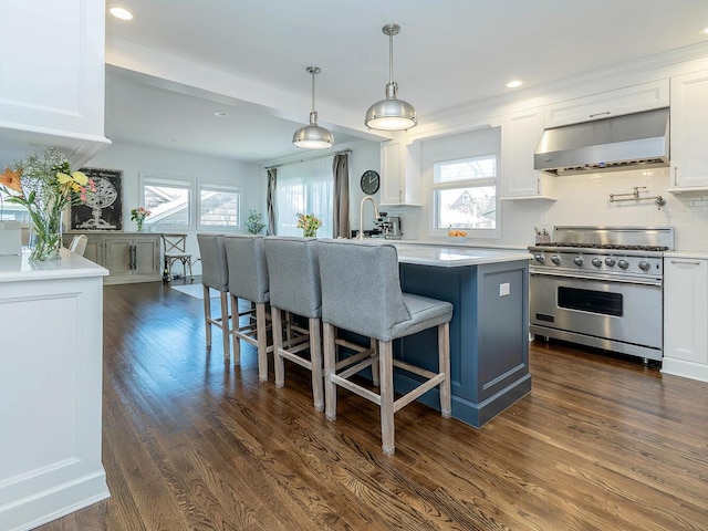 kitchen featuring high end stove, range hood, white cabinetry, plenty of natural light, and recessed lighting