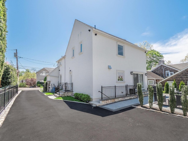 rear view of house featuring stucco siding and fence