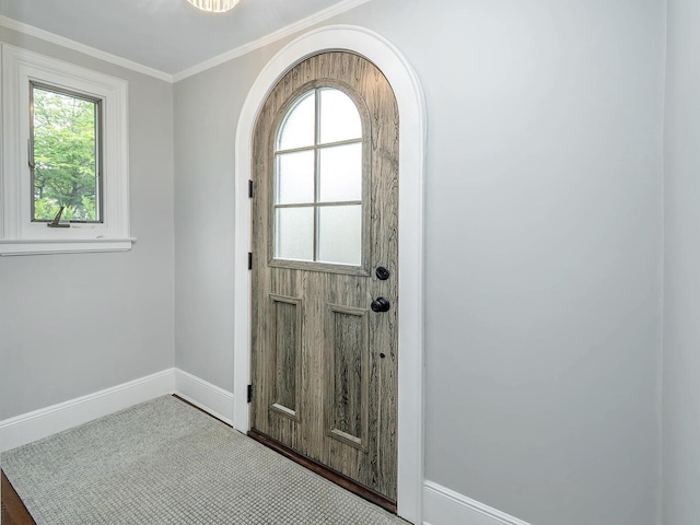 doorway featuring plenty of natural light, baseboards, arched walkways, and crown molding