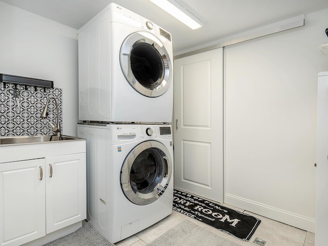 clothes washing area with stacked washer / dryer, cabinet space, and light tile patterned floors