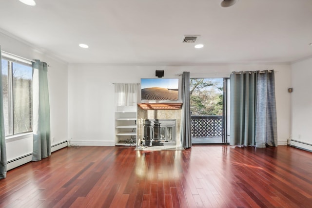 unfurnished living room featuring a baseboard radiator, a tile fireplace, wood finished floors, and visible vents