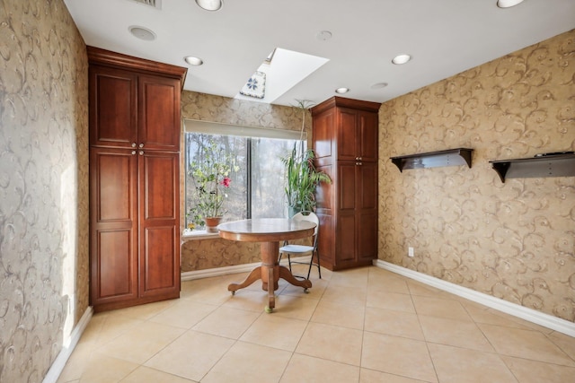 interior space with a skylight, baseboards, light tile patterned floors, and recessed lighting