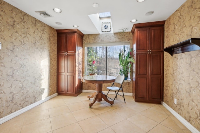 living area featuring light tile patterned flooring, a skylight, visible vents, and baseboards