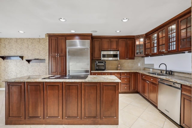 kitchen featuring stainless steel appliances, light stone countertops, light tile patterned floors, and a sink