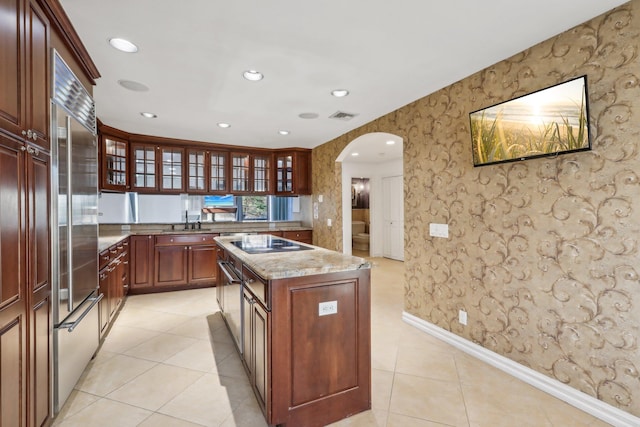 kitchen featuring visible vents, baseboards, black electric stovetop, wallpapered walls, and arched walkways