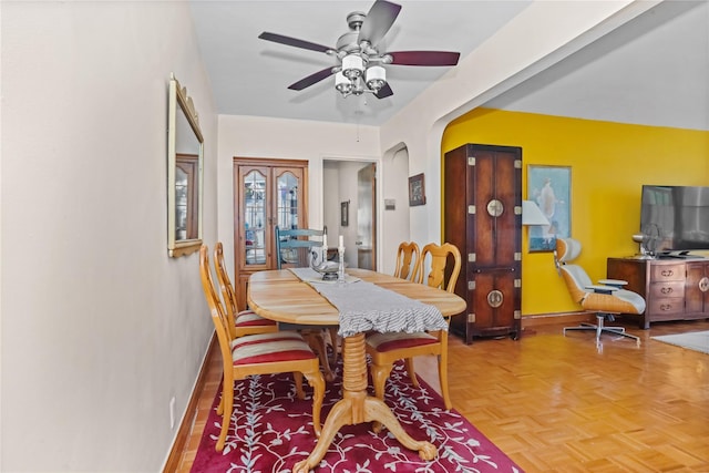 dining area featuring arched walkways and a ceiling fan