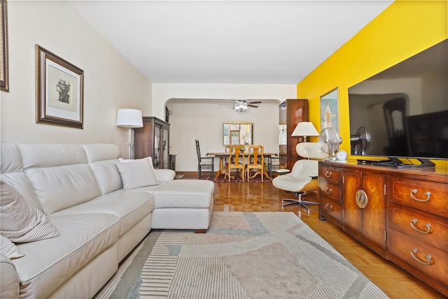 living area with a ceiling fan and arched walkways