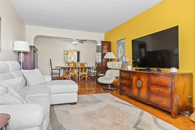 living area featuring a ceiling fan and arched walkways