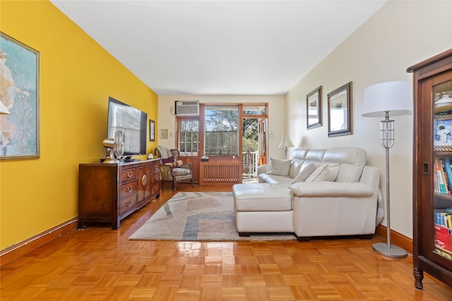 living room featuring radiator, baseboards, and a wall unit AC