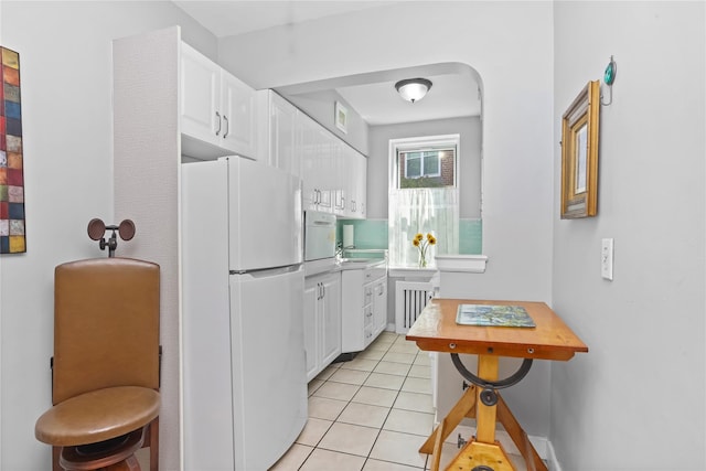 kitchen with freestanding refrigerator, white cabinetry, light tile patterned floors, and light countertops