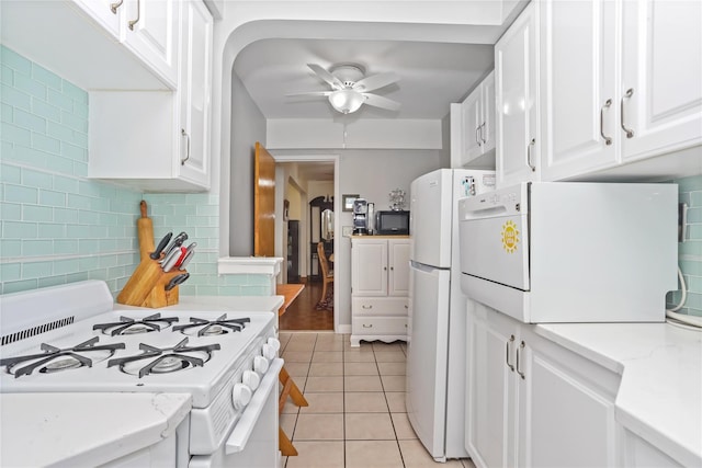 kitchen with a ceiling fan, tasteful backsplash, light tile patterned floors, white cabinets, and white appliances