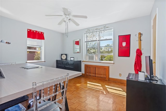 home office with baseboards, a ceiling fan, radiator heating unit, and a healthy amount of sunlight