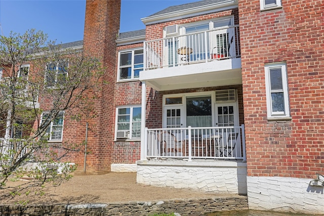 exterior space featuring a chimney, brick siding, and a balcony