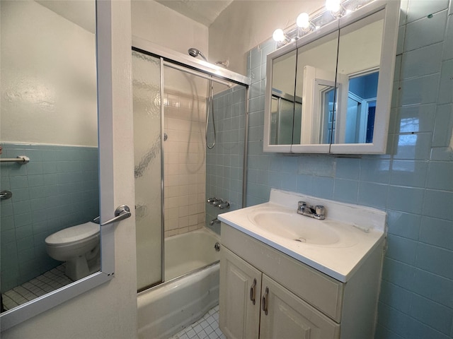 full bath with tile walls, vanity, enclosed tub / shower combo, toilet, and tile patterned flooring