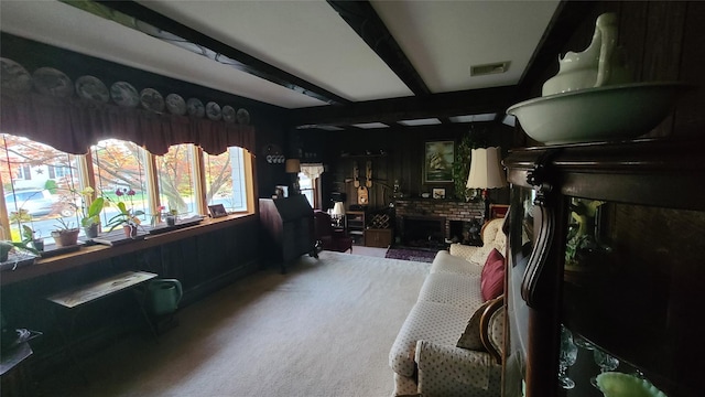 interior space with beamed ceiling, carpet floors, a fireplace, and visible vents