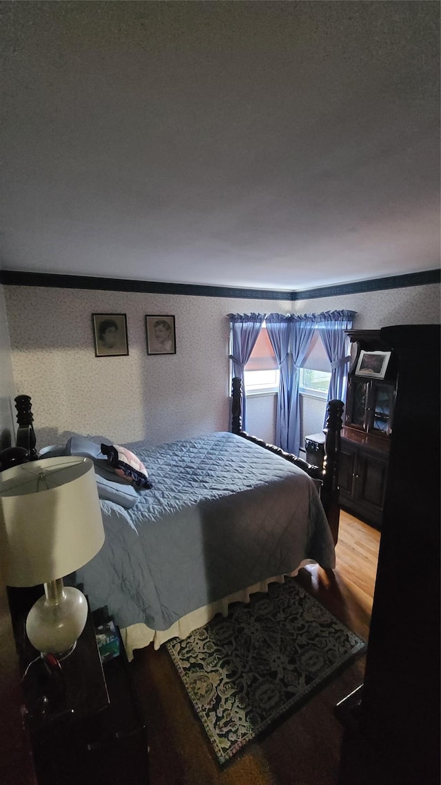 bedroom with ornamental molding and wood finished floors