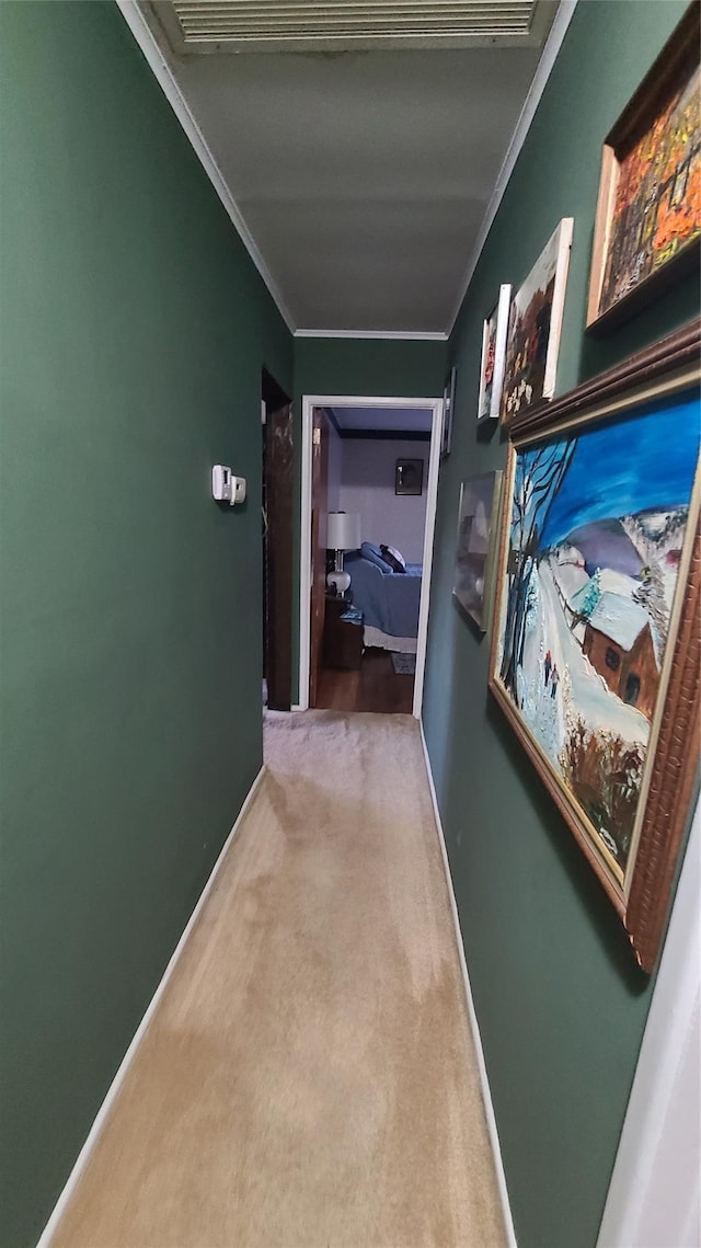 corridor featuring baseboards, ornamental molding, and carpet flooring