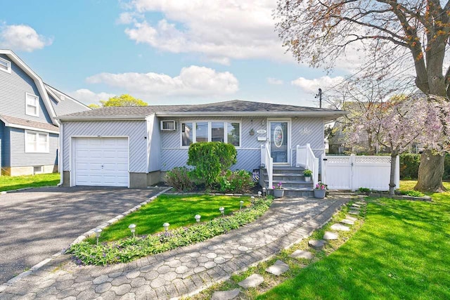 view of front facade featuring fence, aphalt driveway, a front lawn, and a garage