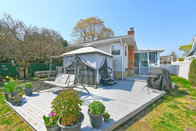 rear view of property featuring a gazebo, a chimney, a fenced backyard, and a wooden deck
