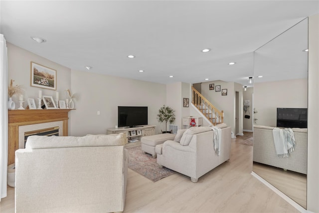 living area with a fireplace, recessed lighting, stairway, and light wood-style floors