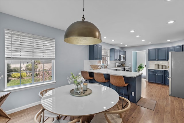 dining room featuring light wood-type flooring, recessed lighting, baseboards, and a wealth of natural light