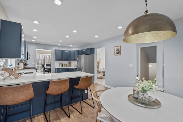 kitchen featuring a peninsula, blue cabinetry, recessed lighting, and light wood-style flooring