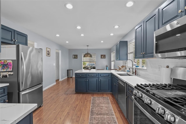 kitchen with a sink, a peninsula, stainless steel appliances, and recessed lighting