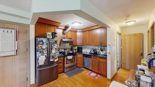 143-36 37th Ave Unit 5C, Flushing, NY 11354 - kitchen with under cabinet range hood, decorative backsplash, light wood-style flooring, dark countertops, and appliances with stainless steel finishes
