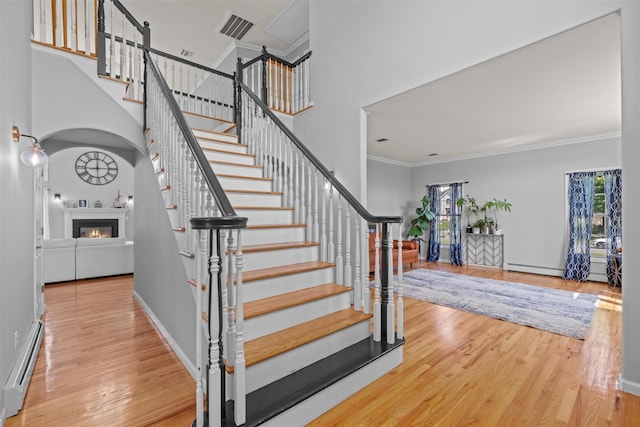 3 Kings Dr, Middletown, NY 10941 - staircase featuring a baseboard radiator, a glass covered fireplace, wood finished floors, ornamental molding, and a high ceiling