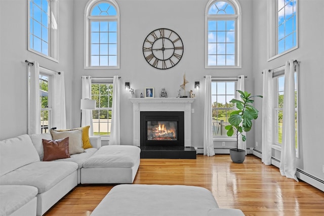3 Kings Dr, Middletown, NY 10941 - living room featuring a towering ceiling, plenty of natural light, a glass covered fireplace, wood finished floors, and baseboard heating