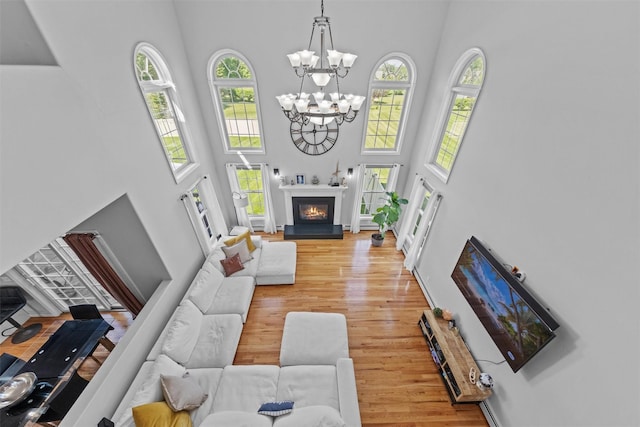 3 Kings Dr, Middletown, NY 10941 - living room with a high ceiling, light wood-style flooring, a chandelier, and a glass covered fireplace