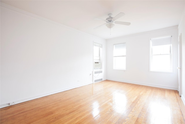 spare room with light wood-style floors, radiator, ornamental molding, ceiling fan, and baseboards