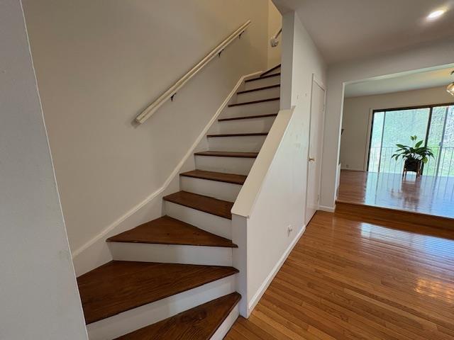 stairway with wood finished floors and baseboards