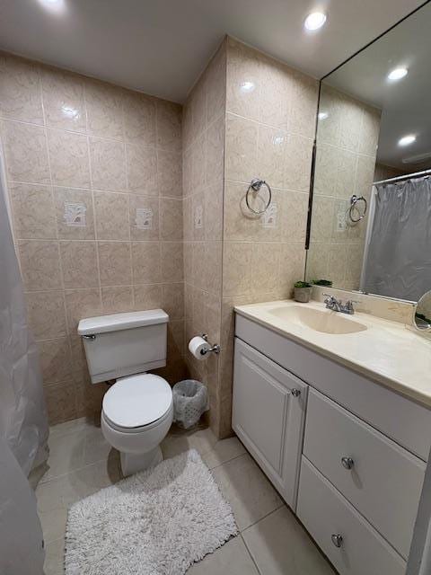 full bathroom featuring toilet, vanity, tile walls, and tile patterned floors