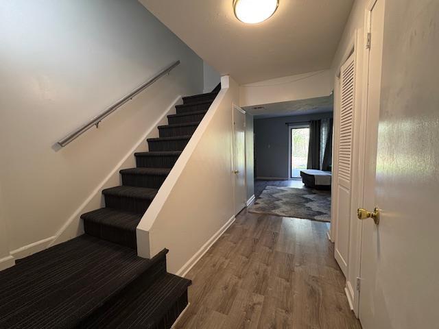 stairs with wood finished floors and baseboards