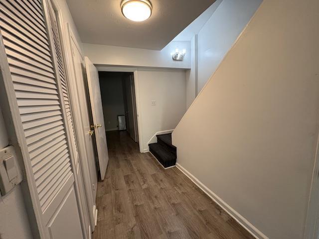 hall with stairway, wood finished floors, and baseboards