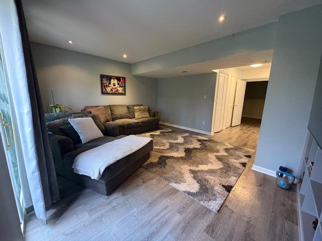 living room featuring baseboards, recessed lighting, and wood finished floors