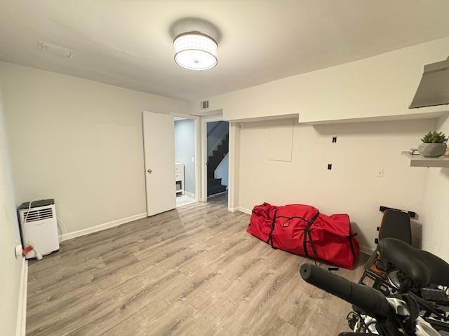 miscellaneous room with baseboards, visible vents, wood finished floors, and stairs