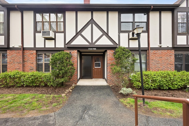 doorway to property with stucco siding, a chimney, and brick siding