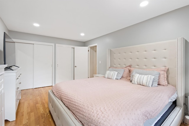 bedroom featuring light wood-style floors, multiple closets, and recessed lighting