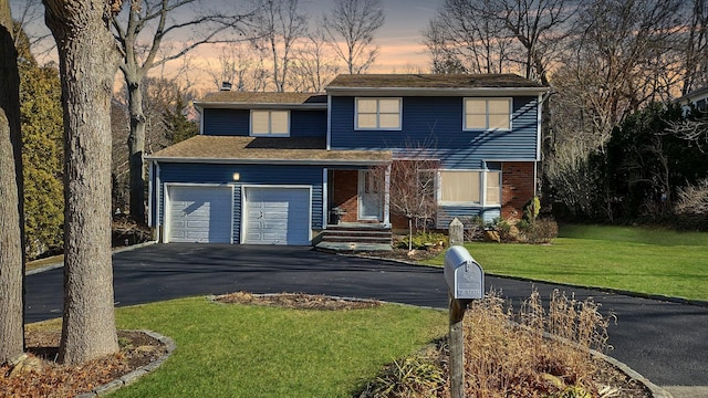traditional-style home with driveway, a front lawn, and brick siding