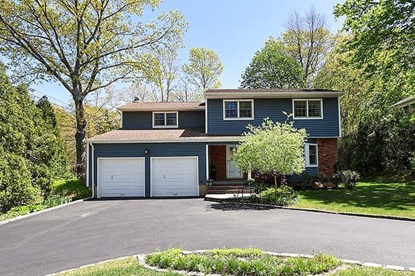 traditional-style home with an attached garage, driveway, and a front lawn