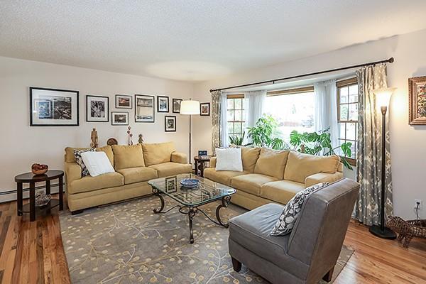 living room featuring a textured ceiling, a baseboard heating unit, and wood finished floors