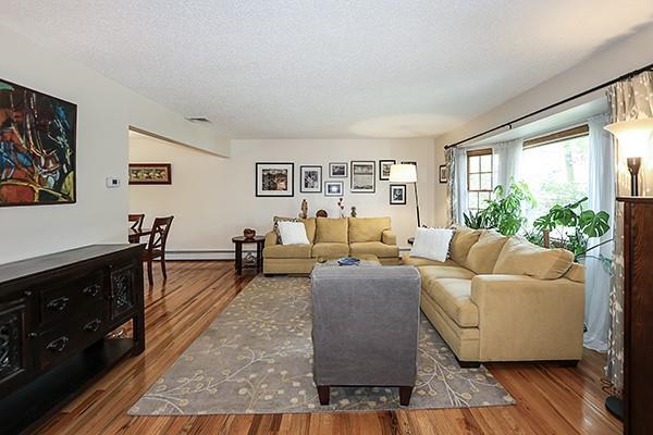 living area featuring a baseboard radiator, a textured ceiling, and wood finished floors
