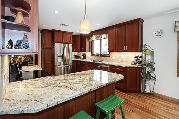 kitchen with a peninsula, light stone counters, a sink, backsplash, and stainless steel appliances