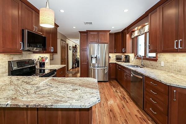 kitchen with light stone counters, a sink, stainless steel appliances, a peninsula, and backsplash