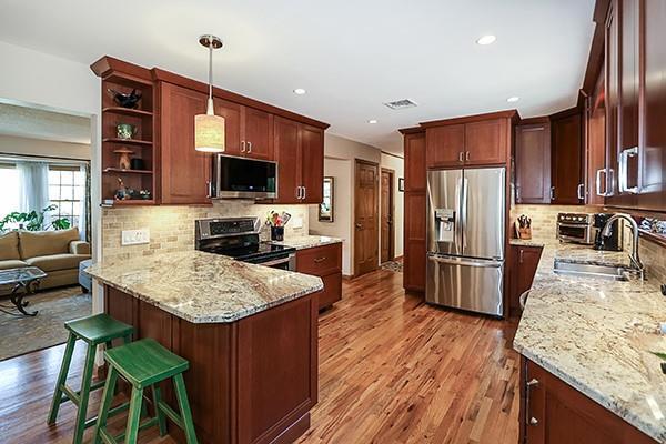 kitchen featuring light stone countertops, a sink, a peninsula, light wood-style floors, and stainless steel appliances